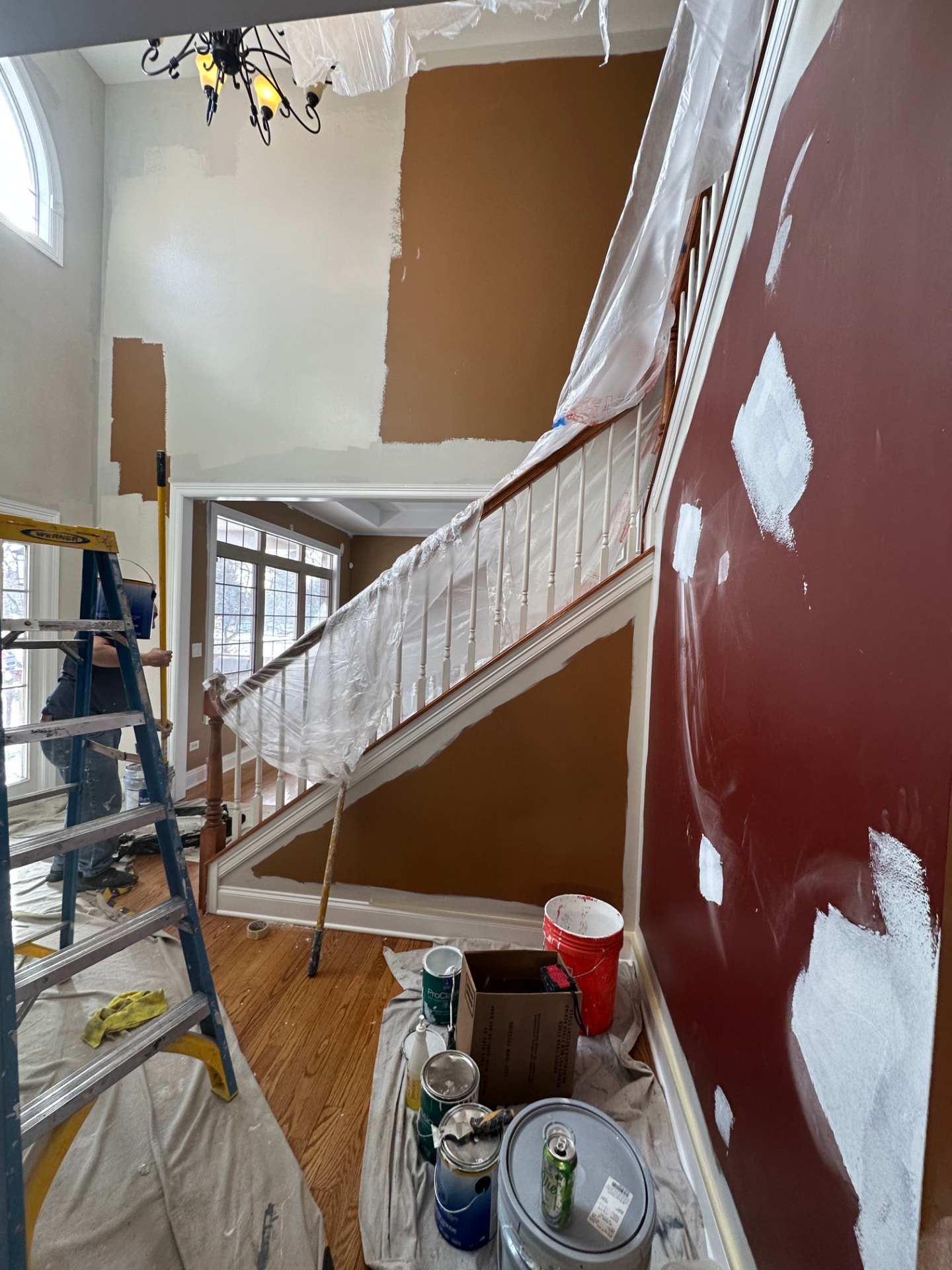 Painter working on interior walls of a home with drop cloths and paint cans